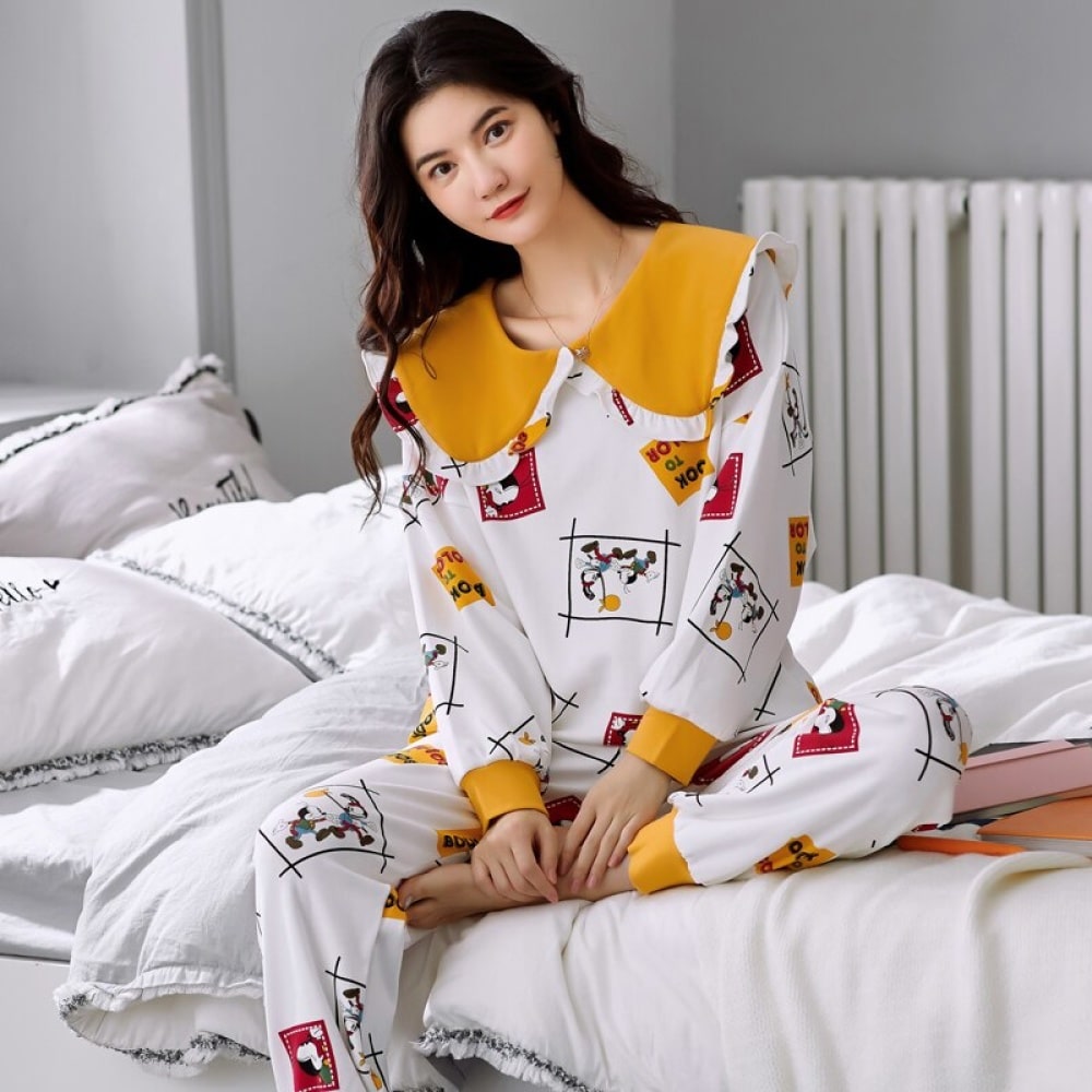 Langärmeliger Baumwollpyjama für Frauen mit Umschlag, sehr hohe Qualität, getragen von einer Frau, die auf einem Bett in einem Haus sitzt