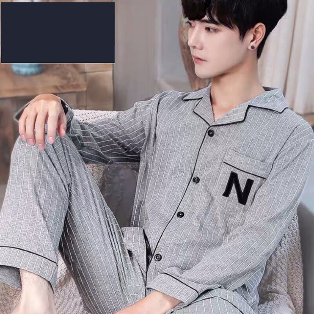 Grau-weiß gestreifter Baumwollpyjama für Männer, der von einem Mann getragen wird, der auf einem Sofa in einem Haus sitzt