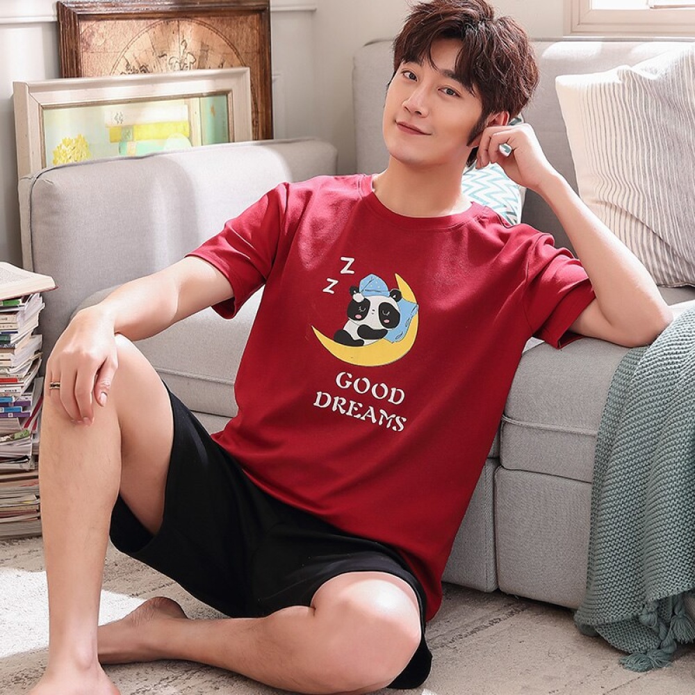 Pyjama aus Baumwolle mit rotem T-Shirt und schwarzen Shorts mit Panda-Muster, sehr hohe Qualität, getragen von einem Mann, der auf einem Teppich in einem Haus sitzt