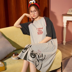 Pyjama-Nachtkleid aus Baumwolle mit Hundemuster, getragen von einer Frau auf einem Sofa in einem Haus