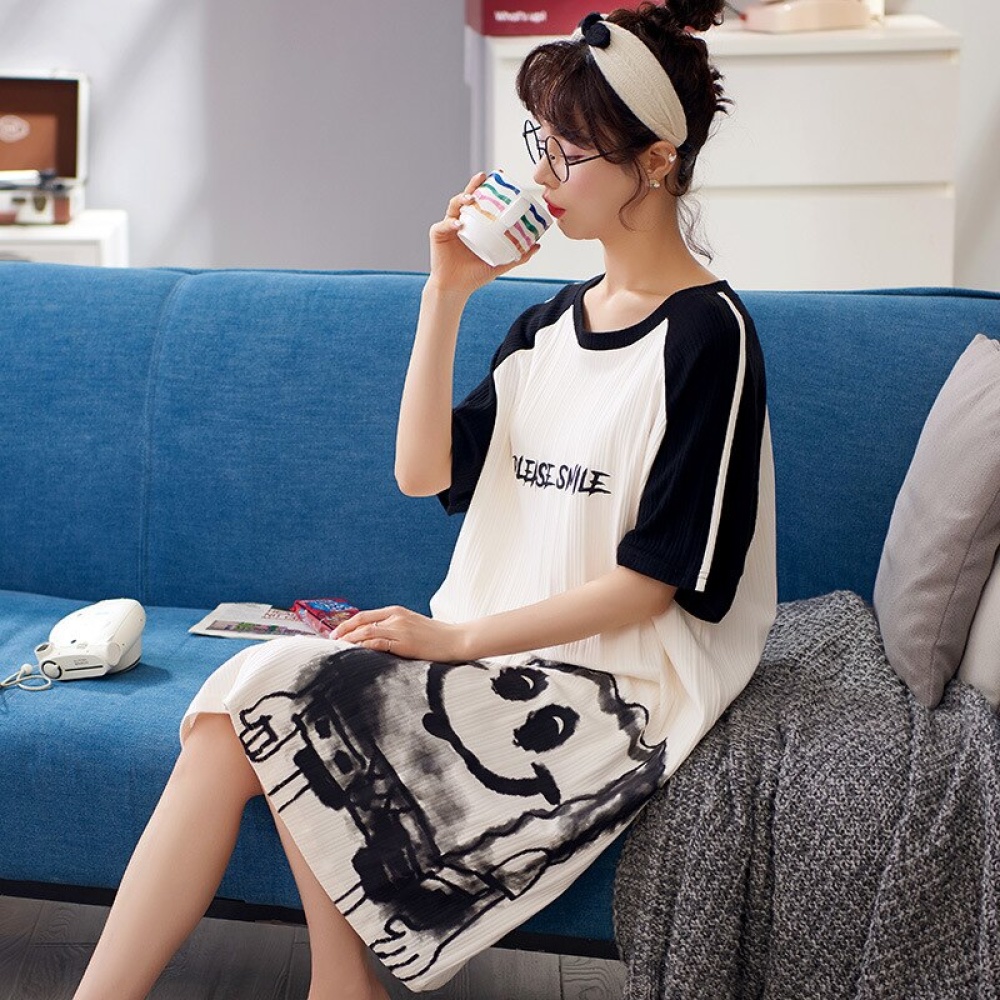 Kurzärmeliger Baumwollpyjama mit der Aufschrift please smile, getragen von einer Frau, die auf einem Sofa in einem Haus sitzt