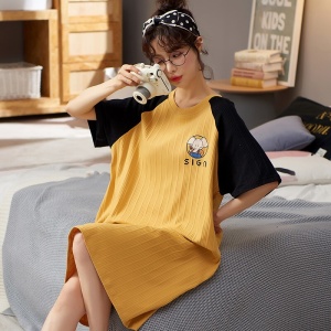 Sommerpyjama Kurzärmeliges gelb-schwarzes Nachtkleid für Frauen, das von einer Frau getragen wird, die auf einem Bett in einem Haus sitzt