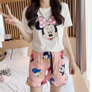 Sommerpyjama mit Minnie, Mickey und Donald in Rosa und Weiß bedruckt, getragen von einer Frau in einem Haus