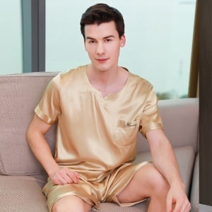 Goldener Pyjama aus Satin für einen goldenen Mann, der von einem Mann getragen wird, der auf einem Sofa in einem Haus sitzt