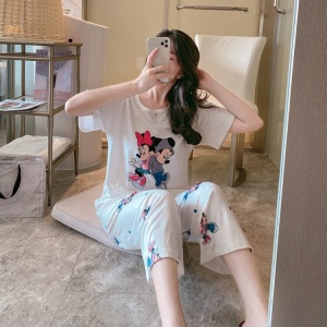 Weißer zweiteiliger Pyjama mit Minnie- und Mickey-Muster, getragen von einer Frau in einem Haus