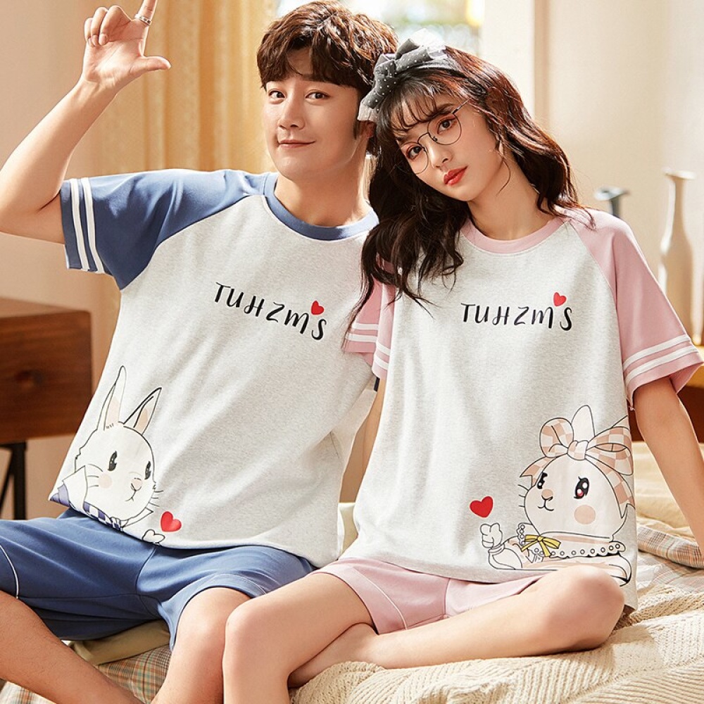 Zweiteiliger Pyjama aus Baumwolle mit T-Shirt und Shorts mit modischem Bärenmotiv, getragen von einem Paar, das auf einem Bett in einem Haus sitzt