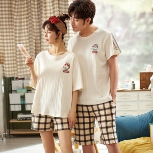 Off-white T-Shirt Pyjama und schwarzbeige karierte Shorts aus Baumwolle, die von einem modischen Paar in einem Haus getragen werden