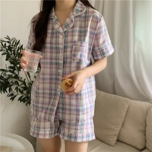 Kurzarm-Pyjama mit Umlegekragen für Frauen, der von einer Frau vor einem Sofa in einem Haus getragen wird