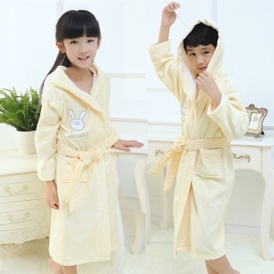 Gelber Kaninchenpyjama aus Baumwolle für modische Kinder, getragen von einem kleinen Jungen und einem kleinen Mädchen in einem modischen Haus