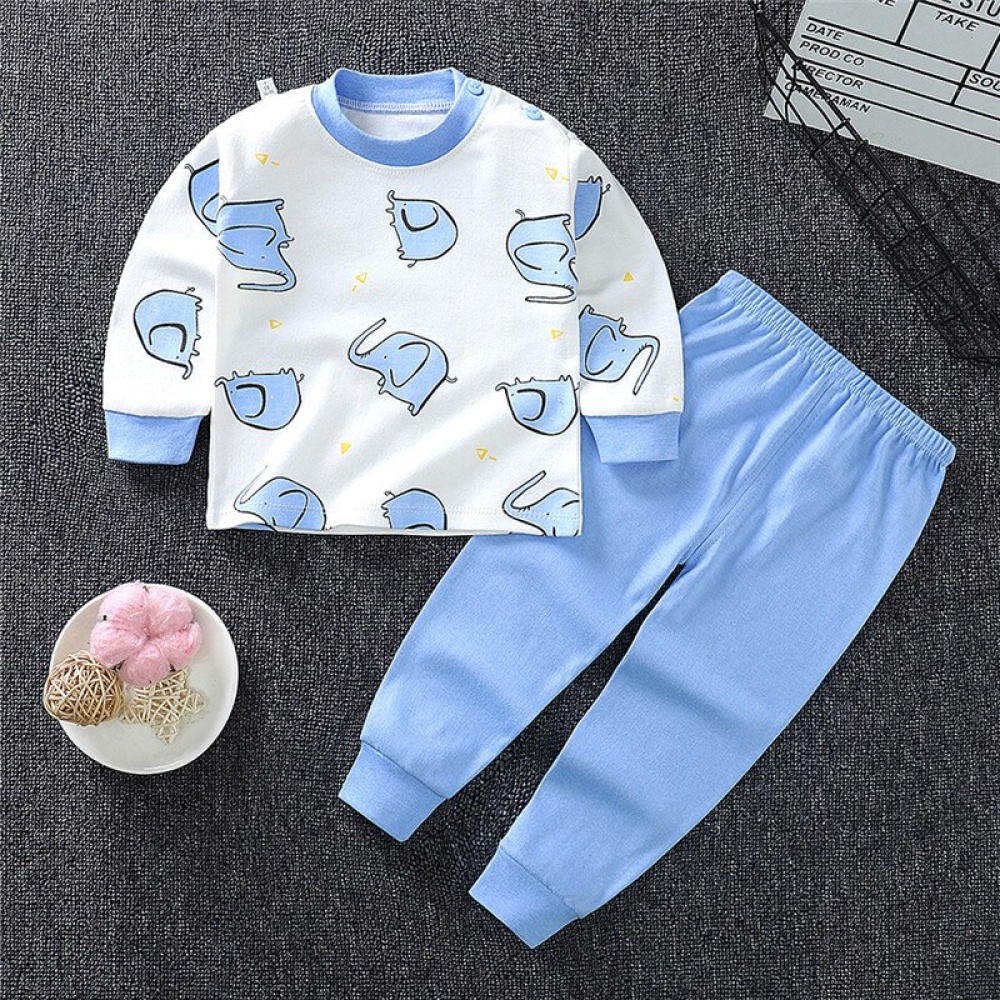 Pyjama für kleine Jungen aus Baumwolle mit Elefantenmotiv und einfarbig blauer Hose auf einem Teppich in einem Haus
