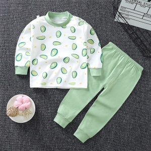 Pyjama für kleine Jungen aus Baumwolle mit Avocado-Muster und einfarbig grüner Hose, modisch auf einem Teppich in einem Haus