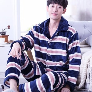 Gestreifter linierter Fleece-Pyjama für Männer, der von einem Mann vor einem Sofa in einem Haus getragen wird