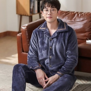 Einfarbig grauer Flanellpyjama für Männer, der von einem Mann vor einem Sofa in einem Haus getragen wird