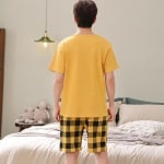 Kurzärmeliger Sommerpyjama Garfield für Männer in Gelb, getragen von einem Mann vor einem Bett in einem Haus