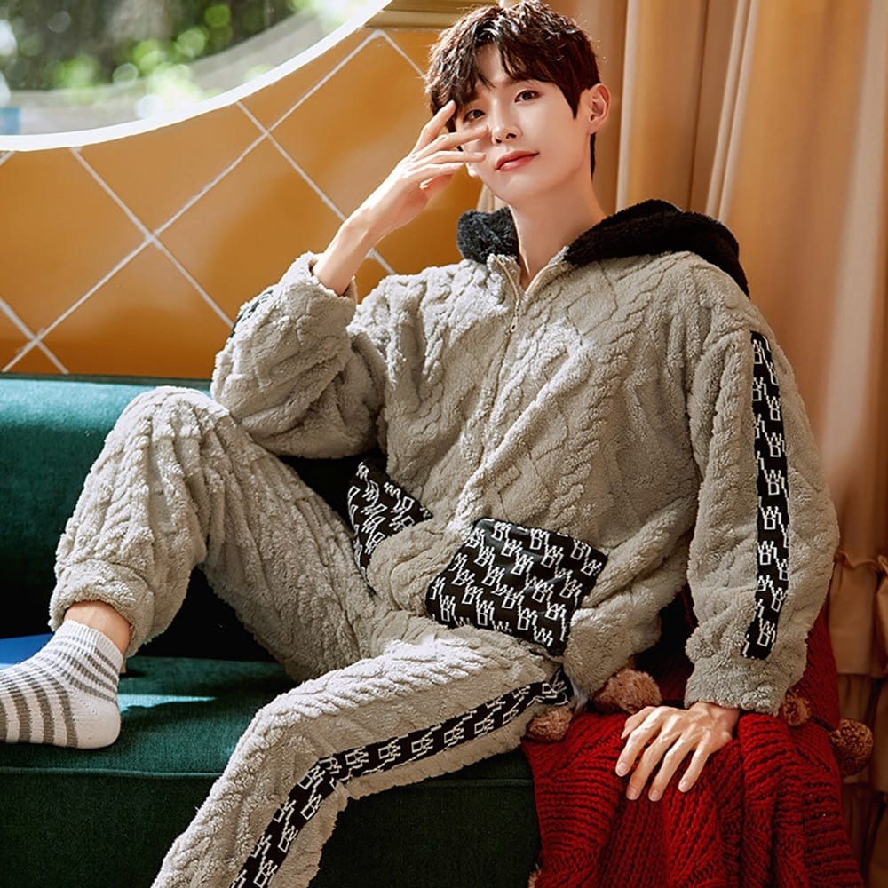 Warmer Herrenpyjama mit Kapuze, der von einem Mann getragen wird, der in einem Haus auf einem Stuhl sitzt