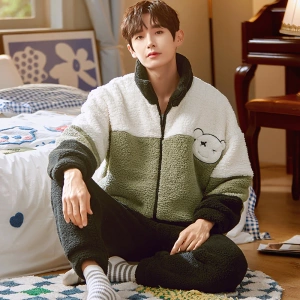 Warmer Winterpyjama mit hohem Kragen, der von einem Mann getragen wird, der auf einem Teppich vor einem Bett in einem Haus sitzt