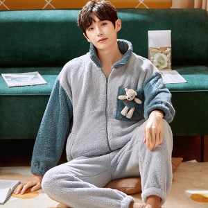 Winterpyjama mit Teddybär für einen Mann, der von einem Mann getragen wird, der auf einem Teppich vor einem Sofa in einem Haus sitzt