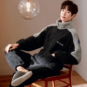 Schwarzer Winterpyjama für Männer, getragen von einem Mann, der auf einem Stuhl in einem Haus sitzt