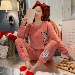 Rosafarbener Mickey-Mouse-Pyjama für Frauen, getragen von einer Frau, die in einem modischen Haus einen roten Haarband trägt