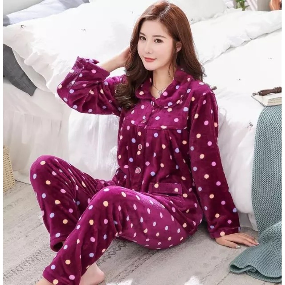 Eleganter violetter Winterpyjama mit kleinen weißen Punkten, getragen von einer Frau, die auf einem Teppich vor einem Bett in einem Haus sitzt