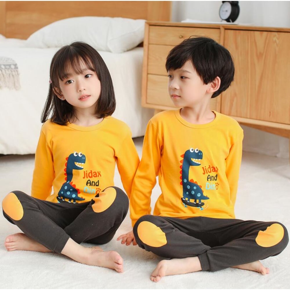 Kinderpyjama mit gelbem Pullover mit Dinosauriermuster und brauner Hose mit zwei Kindern, die den Pyjama tragen