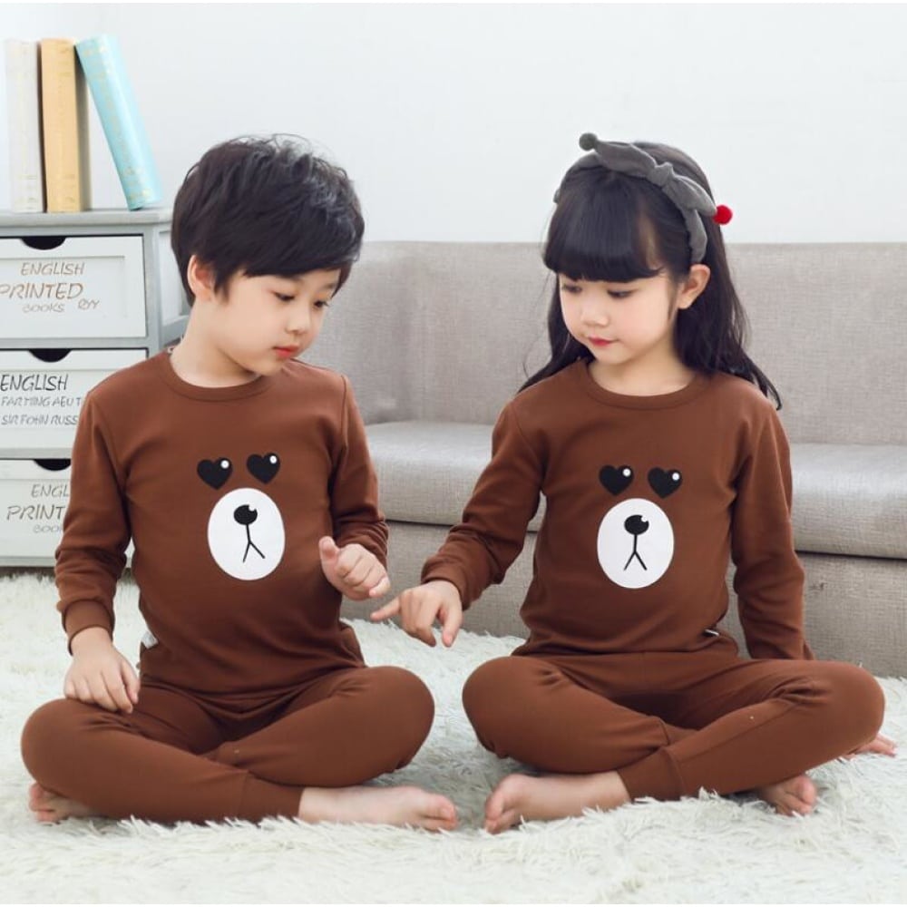 Brauner Frühlingspyjama mit Bärenmuster für Kinder mit zwei Kindern, die den Pyjama tragen und einem Sofa im Hintergrund