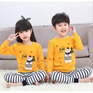 Frühlingspyjama mit gelbem Pullover und weißer Hose mit schwarzen Streifen mit zwei Kindern, die den Pyjama tragen, und einem Hintergrund auf einem Sofa