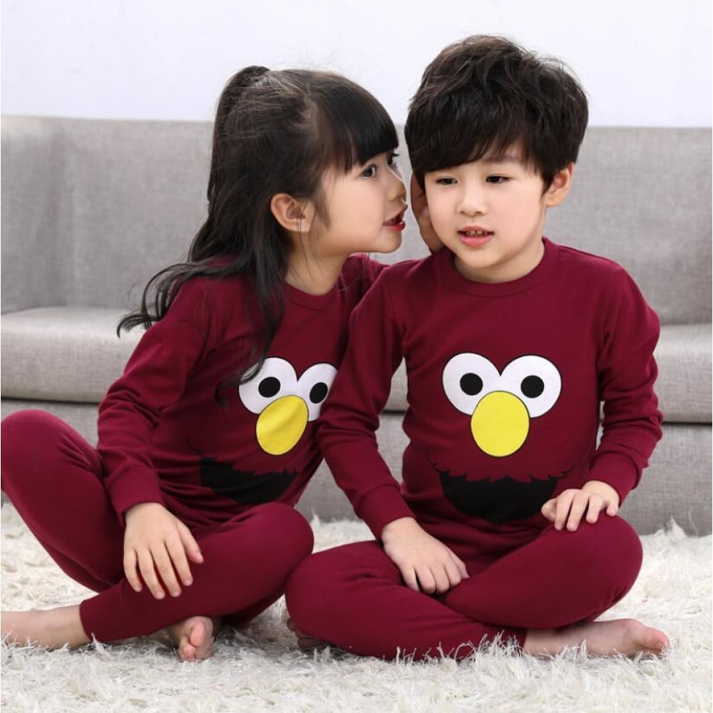 Zweiteiliger burgunderroter Frühlingspyjama für Kinder mit zwei Kindern, die den Pyjama tragen, und einem Sofa im Hintergrund