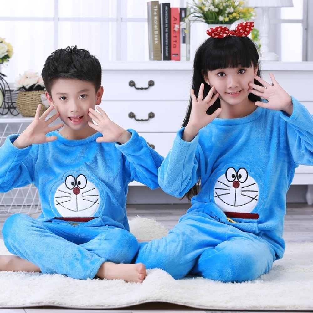 Blauer langärmeliger Flanellpyjama mit Doraemon-Aufdruck für ein Kind, das auf einem Teppich in einem Haus sitzt