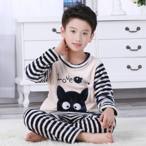 Zweiteiliger Pyjama aus schwarz-weiß gestreiftem Flanell für Jungen, der von einem Jungen getragen wird, der auf einem Teppich in einem Haus sitzt
