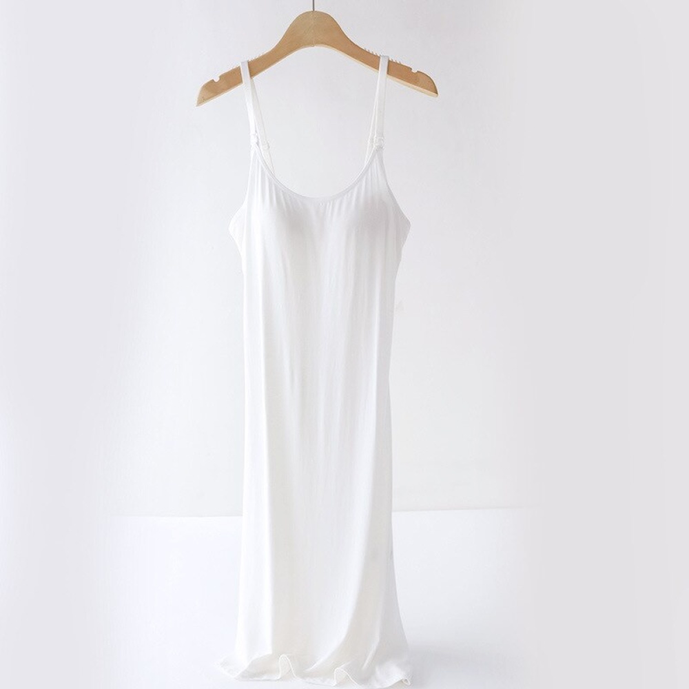 Weißes Nachthemd für Schwangerschaft und Stillzeit, auf einem hölzernen Kleiderbügel, auf weißem Hintergrund
