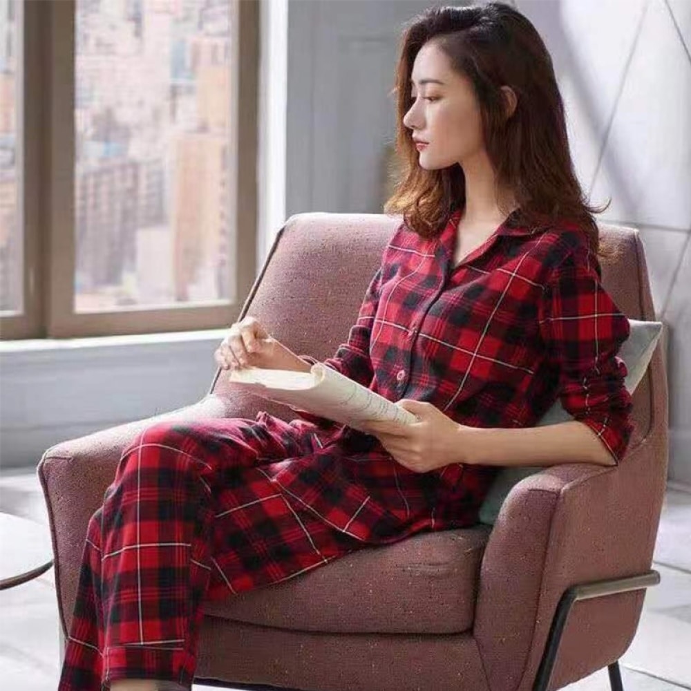 Zweiteiliger Frühlingspyjama mit Karomuster für Frauen, getragen von einer Frau, die auf einem Stuhl in einem Haus sitzt