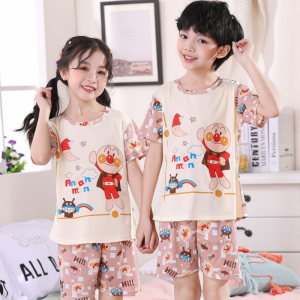 Sommerpyjama mit Zeichentrickmuster für Kinder, getragen von einem Jungen und einem Mädchen in einem Haus mit einem Bilderrahmen an der Wand