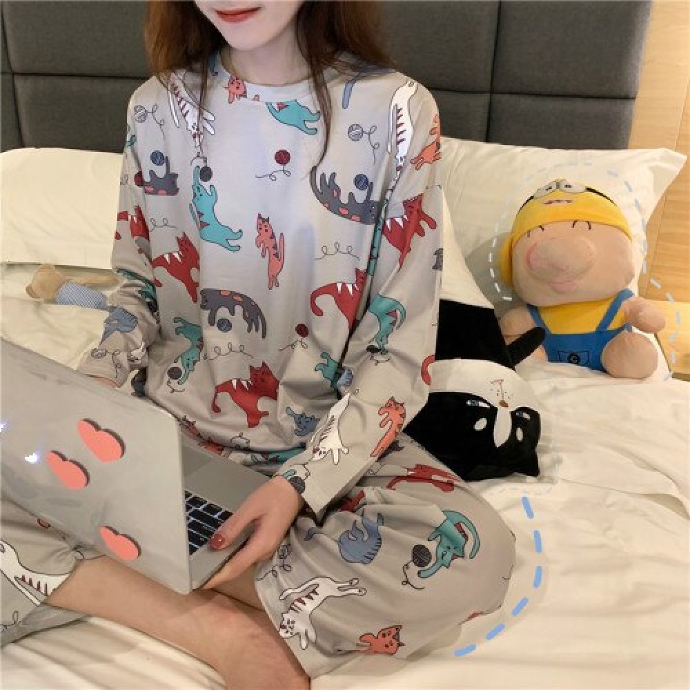 Langärmeliger Herbstpyjama mit Katzenmuster für Frauen, getragen von einer Frau, die auf einem Bett in einem Haus sitzt
