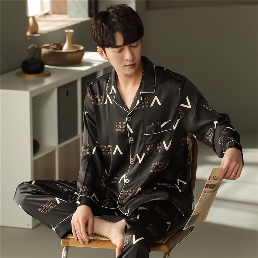 Schwarzer langärmeliger Baumwollpyjama mit Umlegekragen für einen Mann, der von einem Mann getragen wird, der auf einem Stuhl in einem Haus sitzt