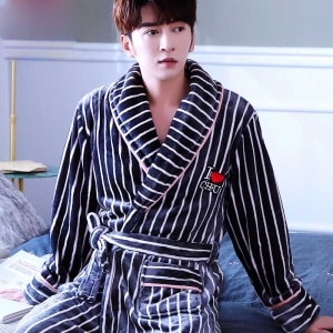 Blauer Flanellpyjama mit weißen Streifen für einen Mann, der auf einem Bett in einem Haus sitzt