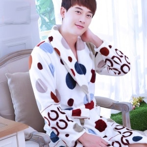 Pyjama Flanellbademantel mit buntem Punktemuster für einen Mann, der von einem Mann getragen wird, der auf einem Stuhl in einem Haus sitzt