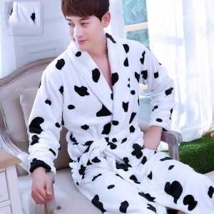 Kimono-Pyjama aus Flanell mit Kuhprint für modische Herren, getragen von einem Mann, der auf einem Stuhl sitzt