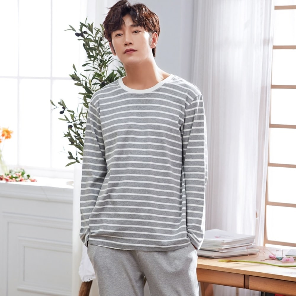 Baumwollpyjama mit grauem, weiß gestreiftem Pullover und grauer Hose, getragen von einem Mann in einem Haus