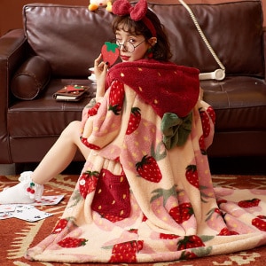 Langer Fleece-Pyjama mit Erdbeermuster für Frauen mit einer Frau, die den bunten Pyjama trägt, mit einem Hintergrund ein Sofa
