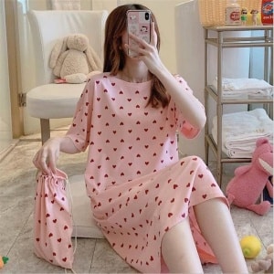 Pyjama-Nachtkleid mit kurzen Ärmeln und Herzdruck, getragen von einer Frau, die auf einem Teppich in einem Haus sitzt