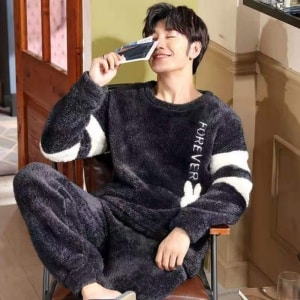 Warmer Fleece-Pyjama für Männer, der von einem Mann getragen wird, der auf einem Stuhl in einem modischen Haus sitzt