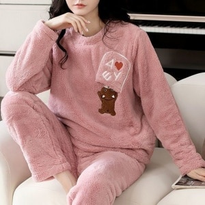 Sehr bequemer Fleece-Pyjama für Frauen mit Bärenmuster, der von einer Frau in einem Haus getragen wird