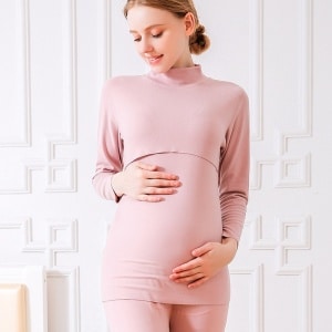 Zweiteiliger rosafarbener Baumwoll-Schwangerschaftspyjama wird von einer schwangeren blonden Frau getragen