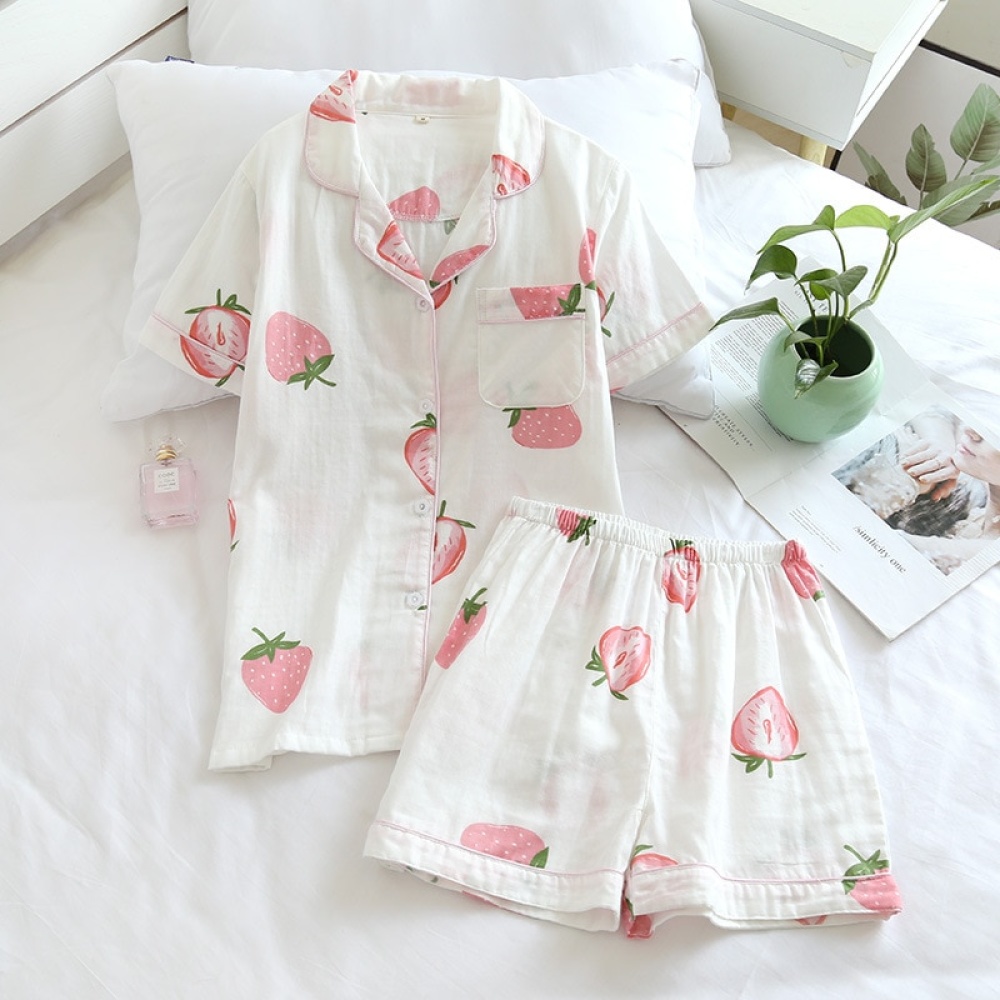 Kurzärmeliger Sommerpyjama mit Erdbeermuster für Frauen auf einem Bett mit einer kleinen Vase und einer Blume im Inneren eines Hauses