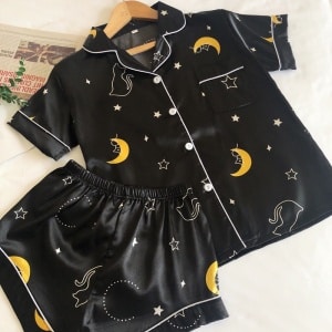 Sommerpyjama aus Satin mit schwarzem Sternenhimmel, weißem Hintergrund und einer Zeitung