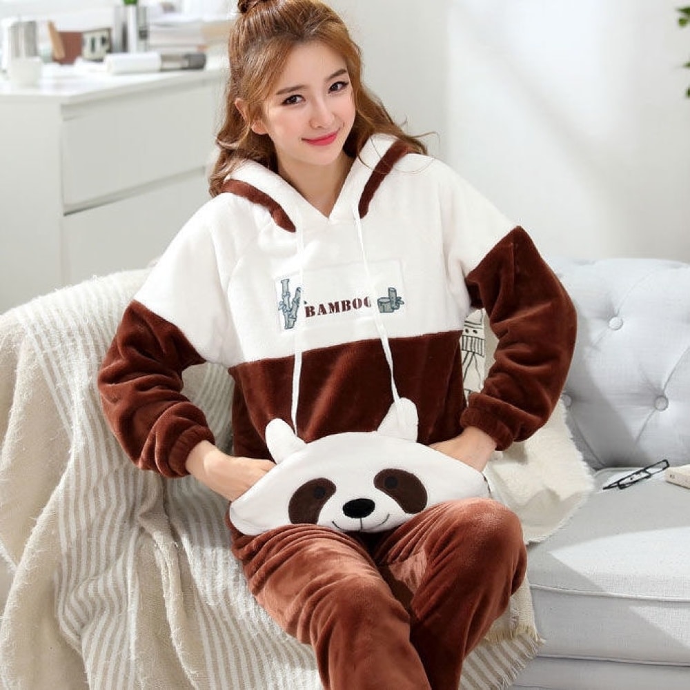 Zweiteiliger Damenpyjama aus Flanell mit Panda-Muster mit einer Frau, die den Pyjama trägt, und einem grauen Sofa mit einer weißen Decke im Hintergrund