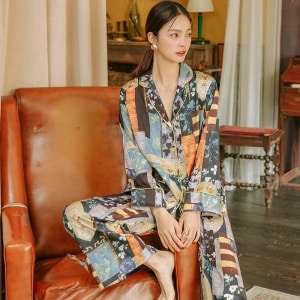 Zweiteiliger Pyjama aus Satin, der von einer Frau getragen wird. Der Pyjama ist mehrfarbig mit Mustern