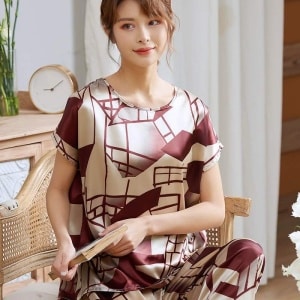 Zweiteiliger Luxus-Pyjama mit kurzen Ärmeln für Frauen, getragen von einer Frau, die auf einem Stuhl in einem Haus sitzt