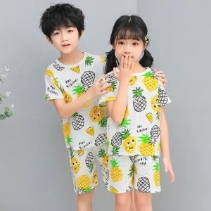 Zweiteiliger weißer Pyjama mit Ananasmuster mit zwei Kindern, die den Pyjama tragen, und einem grauen Hintergrund